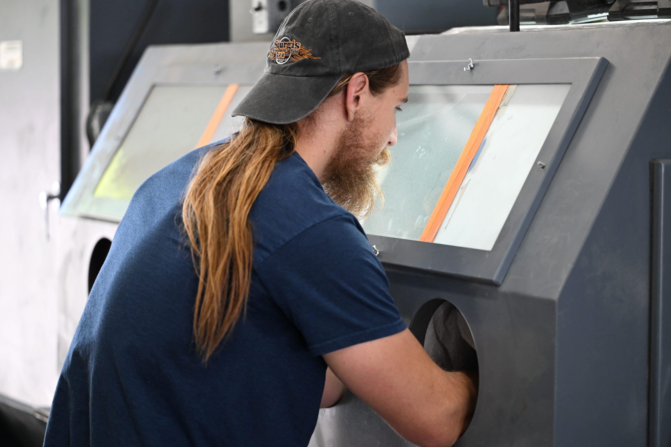 Person operating sandblasting machine in workshop