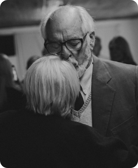Elderly couple dancing closely at an event.