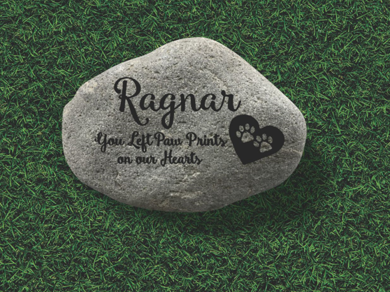 Memorial stone on grass with paw print design.