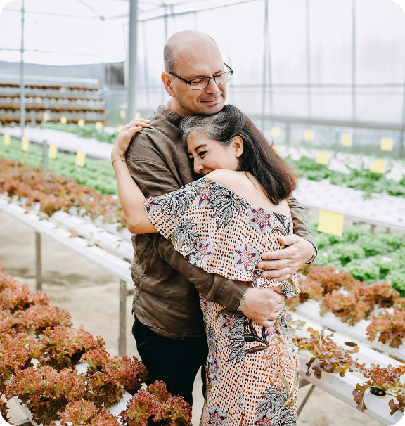 Couple hugging in greenhouse with plants