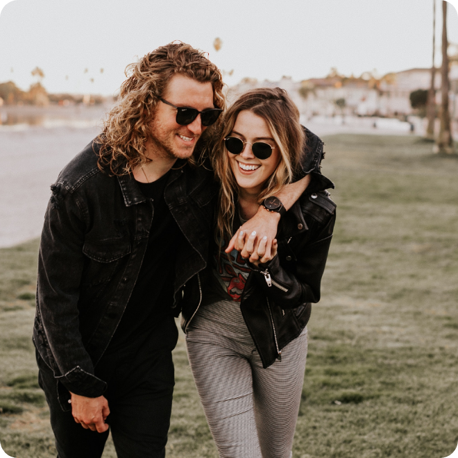 Couple walking outdoors, smiling and wearing sunglasses.