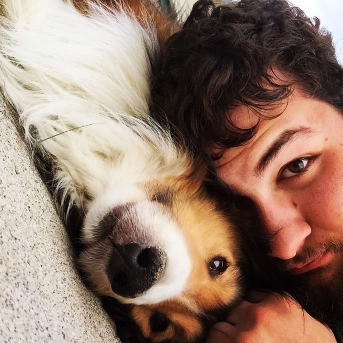 Man and dog cuddling close together outdoors.