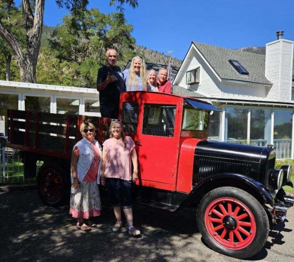 Group with vintage red truck near house