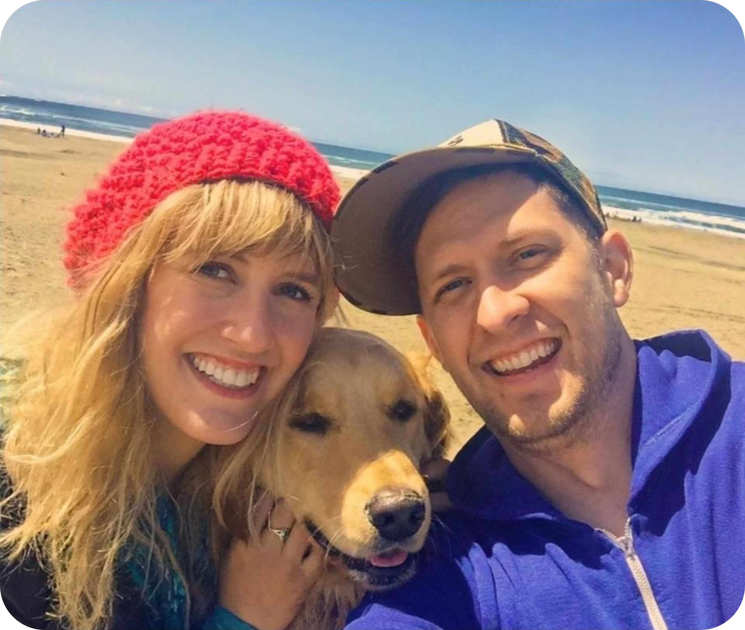 Smiling couple with dog at the beach.