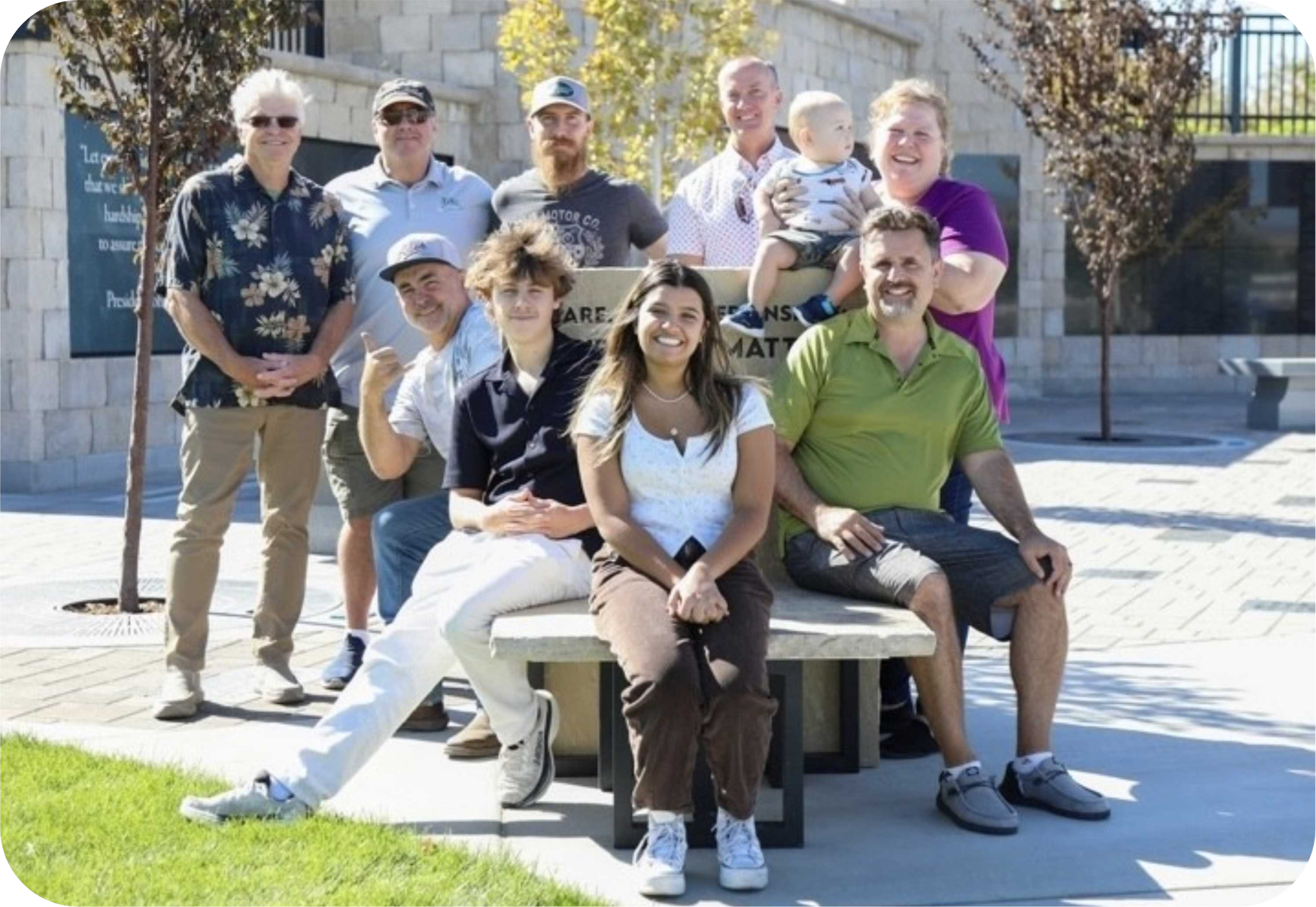 Group of people sitting on a bench outdoors.